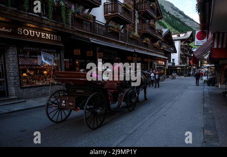Autocar transportant des touristes sur la principale rue commerçante de Zermatt qui est un village écologique sans voiture entouré de restaurants et de boutiques Banque D'Images