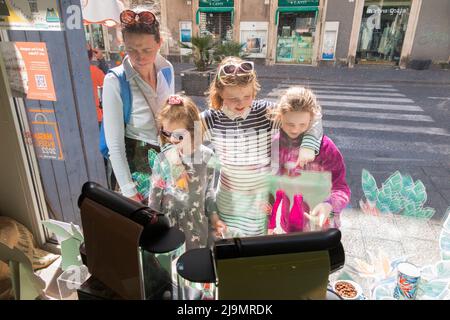 Famille de shopping incluant mère, mère, et trois filles filles, enfants enfants, boutique de fenêtres pour les cafetières et les cafetières exposées au magasin Bialetti à Catane, Sicile. Italie. (129) Banque D'Images