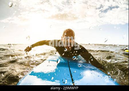 Surfeur gars pagayer avec planche de surf au coucher du soleil à Ténérife avec des gens méconnaissables aux planches de surf en arrière-plan - Sport Travel concept avec peu de profondeur d Banque D'Images