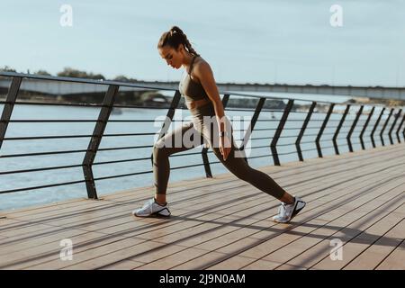 Jolie jeune femme de sport qui fait de l'exercice sur une promenade en bord de rivière Banque D'Images