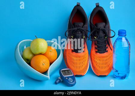 Baskets, fruits dans un bol en forme de coeur et bouteille d'eau sur fond bleu Banque D'Images