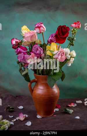 beaucoup de roses multicolores, bouquet dans un vase en céramique sur fond peint vert, photographie artistique de la vie Banque D'Images