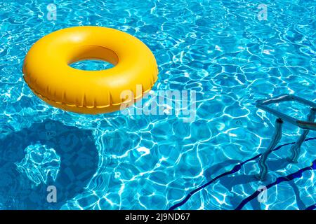 Anneau jaune flottant dans la piscine bleue rafraîchissante Banque D'Images