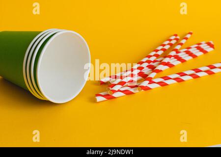 Gobelets en papier vert avec paille en papier à rayures sur fond jaune. Concept écologique Banque D'Images