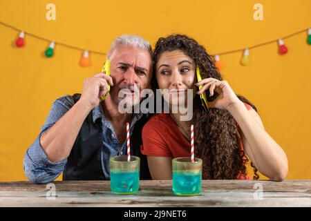 père et fille parlent sur le smartphone en même temps assis à proximité l'un de l'autre - prise de vue en studio Banque D'Images