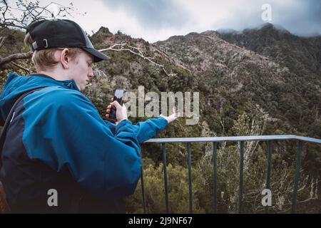 Rare chaffinch de Madeiran vole sur la main d'un homme pour obtenir des miettes de nourriture, l'homme capture ce moment unique dans sa vie sur son téléphone mobile. Levada d Banque D'Images