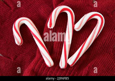 Trio de cannes de bonbon rouge et blanc sur les mitaines rouges Banque D'Images