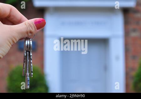 Main de femme avec des touches métalliques sur fond flou avec la maison Banque D'Images