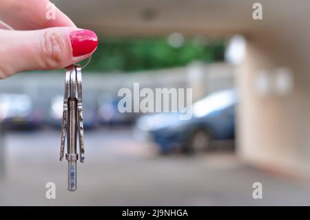 Main de femme avec touches métalliques sur fond flou avec nouvelle voiture Banque D'Images