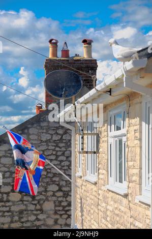 Île de Portland. 24th mai 2022. Météo Royaume-Uni. Un mouette arpentera le drapeau du Jubilé de platine de la Reine, qui flotte sous le soleil chaud, au-dessus de la plage de Chesil, sur l'île de Portland. Crédit : stuart fretwell/Alay Live News Banque D'Images