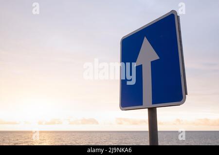 Panneau carré avec flèche blanche sur fond bleu ciel. Il indique une route à sens unique Banque D'Images