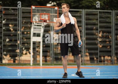Jeune homme en chemise sueur se reposant après un entraînement intense sur la salle de sport extérieure. Beau sportif caucasien avec corps musclé dans la mode sportswear semble fatigué et épuisé. Banque D'Images