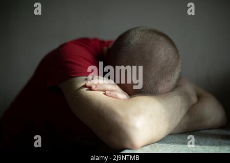 Homme fatigué. Guy dort assis. L'homme s'est endormi avec sa tête sur la table. Après une dure journée. Banque D'Images