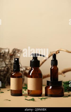 Jeu de flacons à cosmétiques en verre ambré avec étiquettes. Branche d'arbre, écorce de bouleau, mousse sur fond. SPA produits de beauté naturels bio design. Banque D'Images