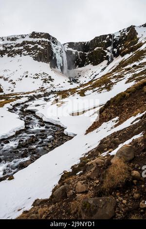 La magnifique cascade de Grundarfoss et la rivière Grundará dans un paysage enneigé de la fin de l'hiver, péninsule de Snæfellsnes, Islande Banque D'Images