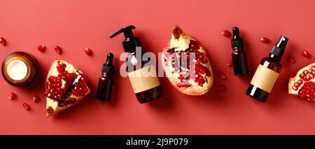 Cosmétiques naturels en grenade sur fond rouge. Flacons en verre ambré avec des tranches de grenade et de graines. Banque D'Images