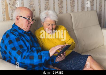 couple senior mignon appréciant l'utilisation du téléphone mobile à la maison moyen plein plan de la technologie intérieure et le concept d'ancienneté. Photo de haute qualité Banque D'Images