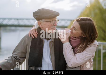 Fille adulte embrassant son père aîné à l'extérieur dans le parc le jour du printemps. Banque D'Images