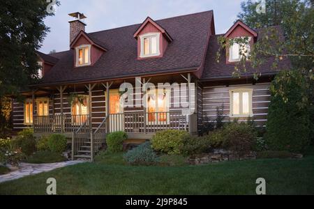 Réplique de l'ancienne maison en rondins de style cottage Canadiana 1800s avec cour avant paysagée en été au crépuscule. Banque D'Images