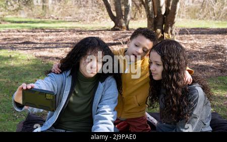 Gros plan portrait du petit frère et des sœurs de l'adolescence font selfie avec le téléphone portable à l'extérieur dans la nature, l'espace de copie. Banque D'Images