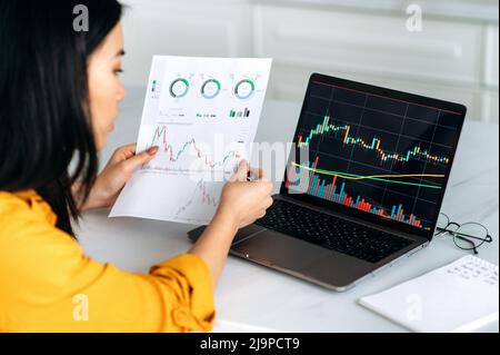 Une femme intelligente prospère négociant crypto, un investisseur, utilise un ordinateur portable, analyse les cartes du commerce sur le marché boursier de l'échange numérique de crypto-monnaie, analyse, achète et vend des pièces de crypto Banque D'Images