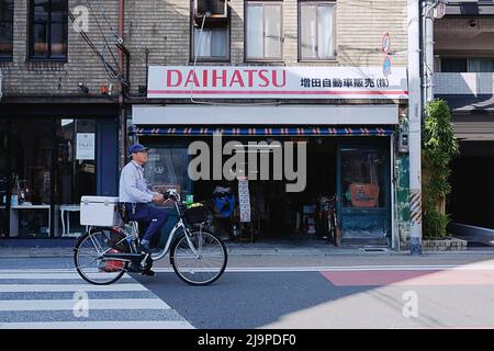 Un Japonais à vélo passe devant une ligne de magasins à Kawaramachi - un quartier du centre-ville de Kyoto, au Japon. Banque D'Images