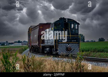 Ronks, Pennsylvanie, octobre 2020 - vue d'un train de marchandises diesel voyageant sur une seule piste avec des voitures Graffiti-ed alors qu'une tempête approche. Banque D'Images