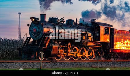 Ronks, Pennsylvanie, octobre 2020 - Une vue d'un train de passagers à vapeur antique approchant à Sunrise avec une tête pleine de vapeur et de fumée traversant les terres agricoles Banque D'Images