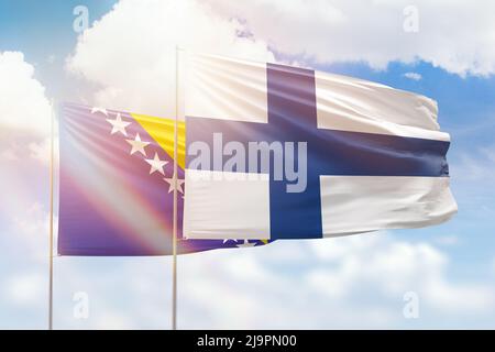 Ciel bleu ensoleillé et drapeaux de la finlande et de la bosnie Banque D'Images