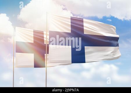 Ciel bleu ensoleillé et drapeaux de la finlande et de la finlande Banque D'Images