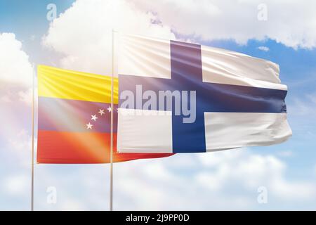 Ciel bleu ensoleillé et drapeaux de la finlande et du venezuela Banque D'Images