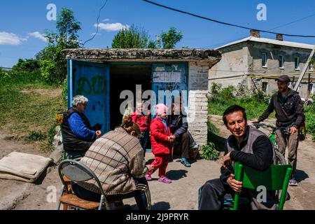 Les gens assis devant un bunker où ils partent dans la banlieue de la ville. Lysysansík, région de Luhansk. 23 mai 2022 Lysygansk est une ville allongée située sur la rive droite de la rivière Donets, dans la région de Luhansk. La ville fait partie d'une zone métropolitaine qui comprend Severodonetsk et Rubizhne; ensemble, les trois villes constituent l'un des plus grands complexes chimiques d'Ukraine. La ville est à environ 7 km de la ligne de front, et les troupes russes se déplacent vers elle, la ville, comme Severodonetsk, est presque isolée. Les Russes tentent d'occuper la route principale qui relie Lysygansk à Kramatorsk Banque D'Images