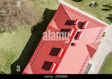 toit de maison en métal rouge avec tuyaux de ventilation et dortoirs. photographie de drone. Banque D'Images