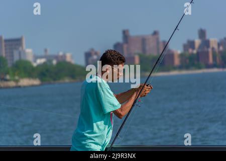 Un homme de Brooklyn, NY, met un appât sur le crochet de pêche Banque D'Images