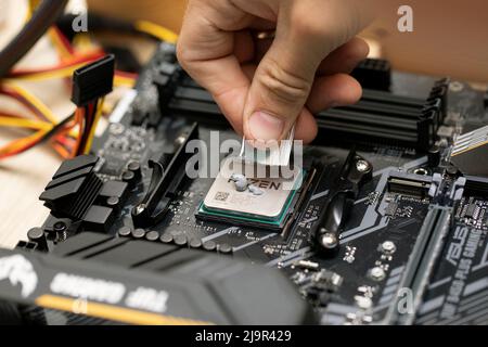 Ingénieur appliquant de la pâte thermoconductrice sur les pièces de puce du microprocesseur du capot du processeur sur la carte mère TUF Gaming B450 plus. Russie, 17.08.2021 Banque D'Images