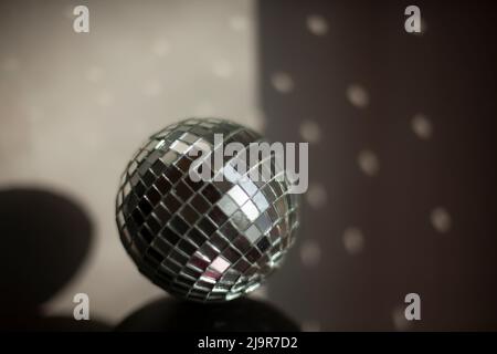 Le bal disco réfléchit la lumière dans la pièce. Une boule de petits miroirs se tient sur la surface du haut-parleur. Détails intérieurs en plein soleil. Banque D'Images