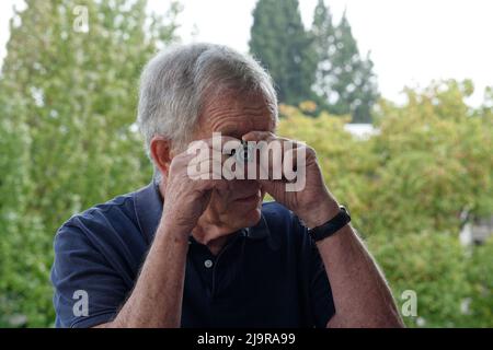 Sub miniature 14mm film Spy caméra utilisée par un homme âgé gris aux cheveux en chemise bleue Banque D'Images