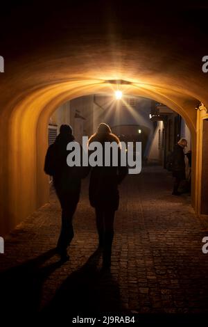 Couple en fin de nuit à pied à travers le passage éclairé de lampe unique sous la maison de tenement sur la rue pavée Dawna dans la vieille ville de Varsovie ville en P Banque D'Images
