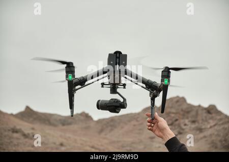 La main des hommes attrape un gros drone professionnel, quelque part dans les montagnes, sur des vidéos Banque D'Images