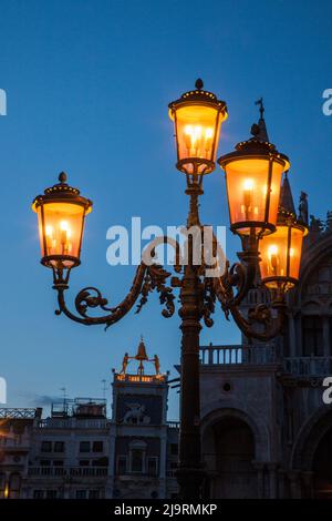 Italie, Venise. La cloche et les statues au sommet du clocktower Saint-Marc sur la Piazza San Marco après le coucher du soleil. Banque D'Images