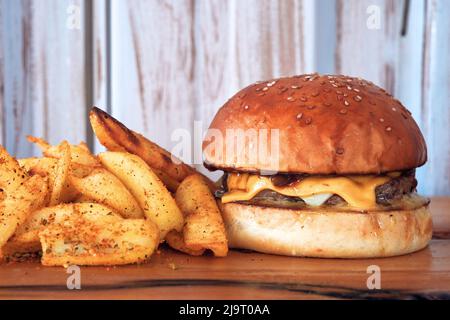 Un hamburger, un hamburger ou un cheeseburger sur une assiette en bois avec des frites frites de pommes de terre frites. Banque D'Images