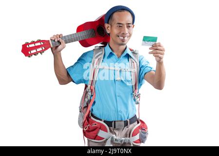 Homme asiatique avec un bonnet beanie et un sac à dos tenant une carte et portant une guitare debout isolée sur fond blanc Banque D'Images