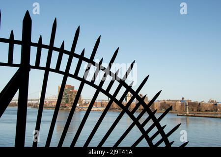 États-Unis, New York City, Manhattan, Upper East Side. John Finley promenade le long de East River, réseau de fer en face de la rivière Banque D'Images