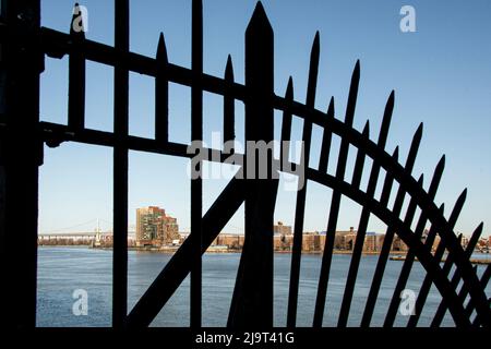 États-Unis, New York City, Manhattan, Upper East Side. John Finley promenade le long de East River, réseau de fer en face de la rivière Banque D'Images