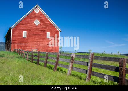 États-Unis, Oregon, Joseph. Grange rouge et clôture près des montagnes Wallowa en Oregon. Banque D'Images