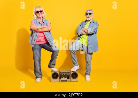 Photo de petite amie douce drôle copain habillé denim tenue à l'écoute perche boîte bras repliés isolé couleur jaune fond Banque D'Images