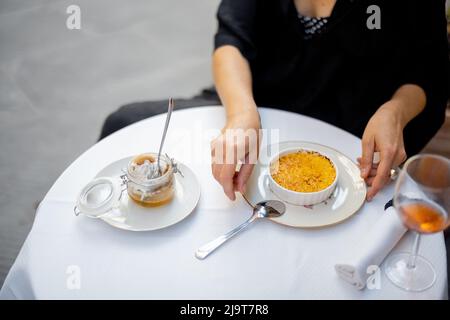 Femme mangeant un dessert avec crème brûlée au restaurant à l'extérieur Banque D'Images