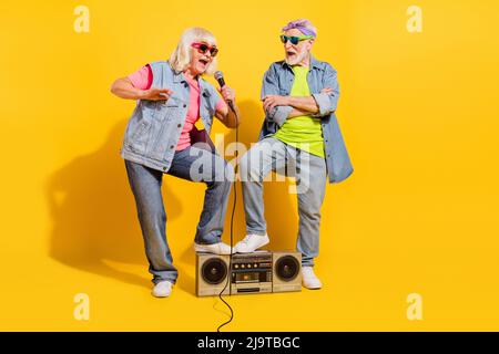 Photo de joli mignon mari femme porter jeans chemises chantant les mains de boombox croisées isolé couleur jaune fond Banque D'Images