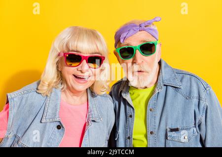 Portrait d'un beau couple gai gris-cheveux portant des vêtements drôles bonne humeur isolé sur fond jaune vif Banque D'Images