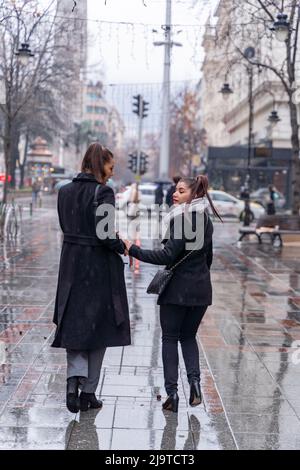 Deux belles et attrayantes femmes marchent ensemble sur la pluie tout en parlant de l'entreprise Banque D'Images